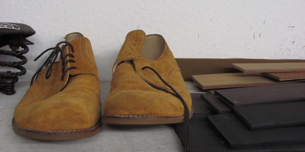 A pair of suede mens shoes besides repair materials 