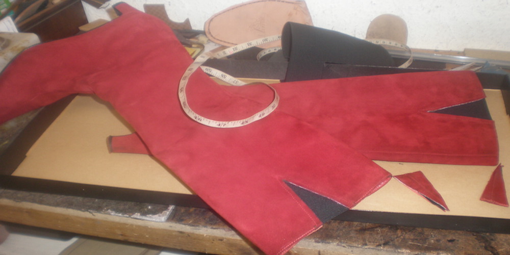 A pair of long red womens boots ready to be repaired 
